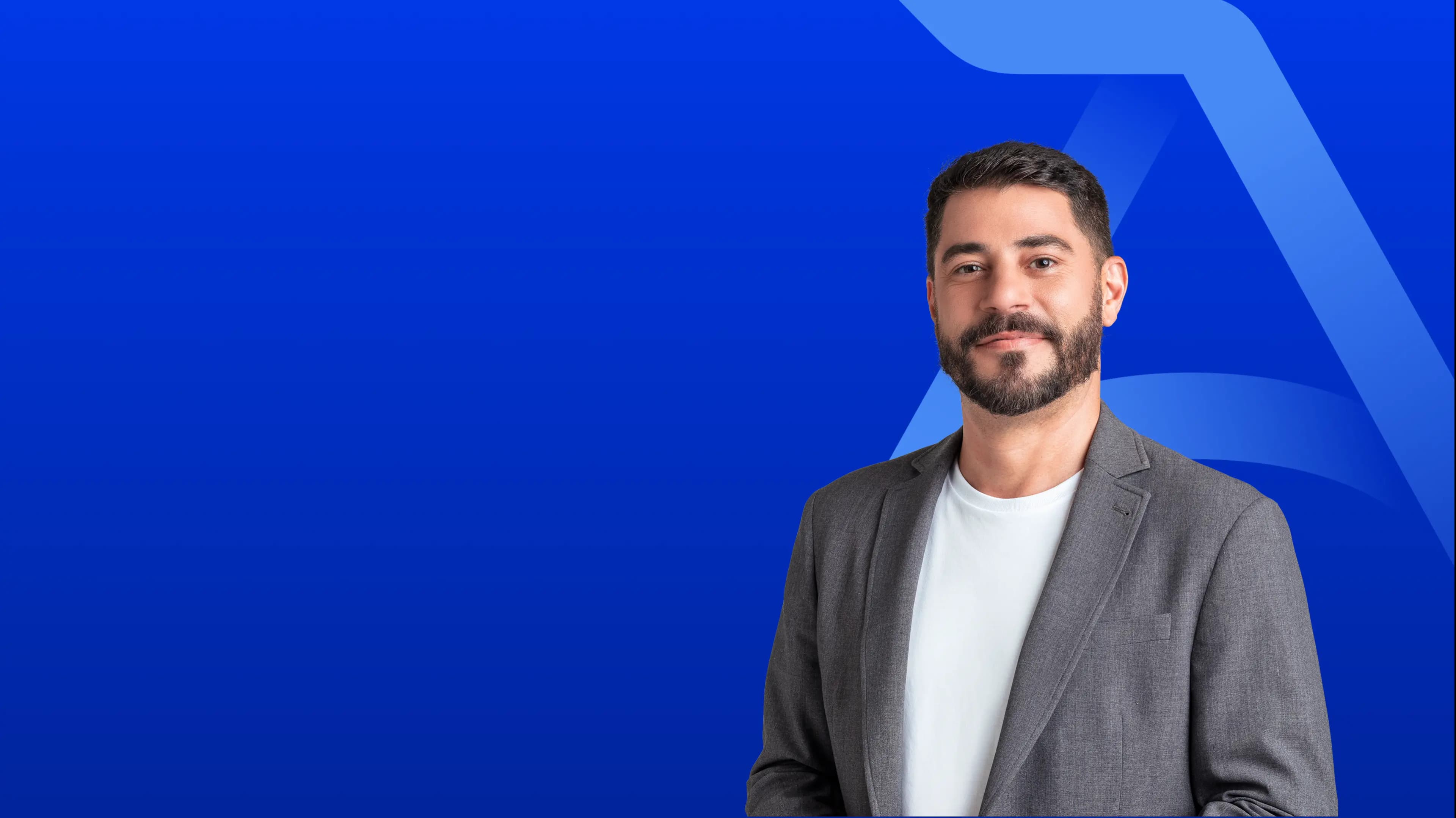 Evaristo Costa veste um terno e está sorrindo sutilmente para a câmera.