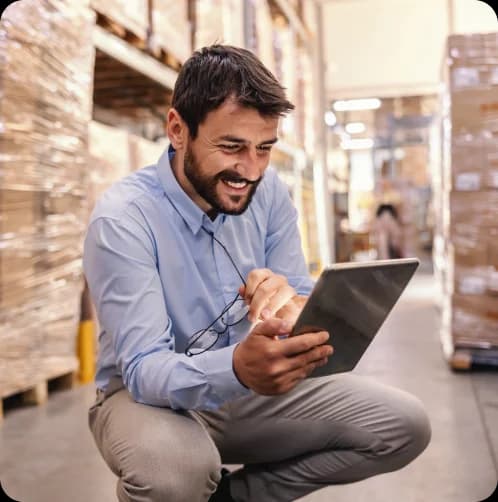 Homem no estoque de uma empresa olhando para o tablet em suas mãos.