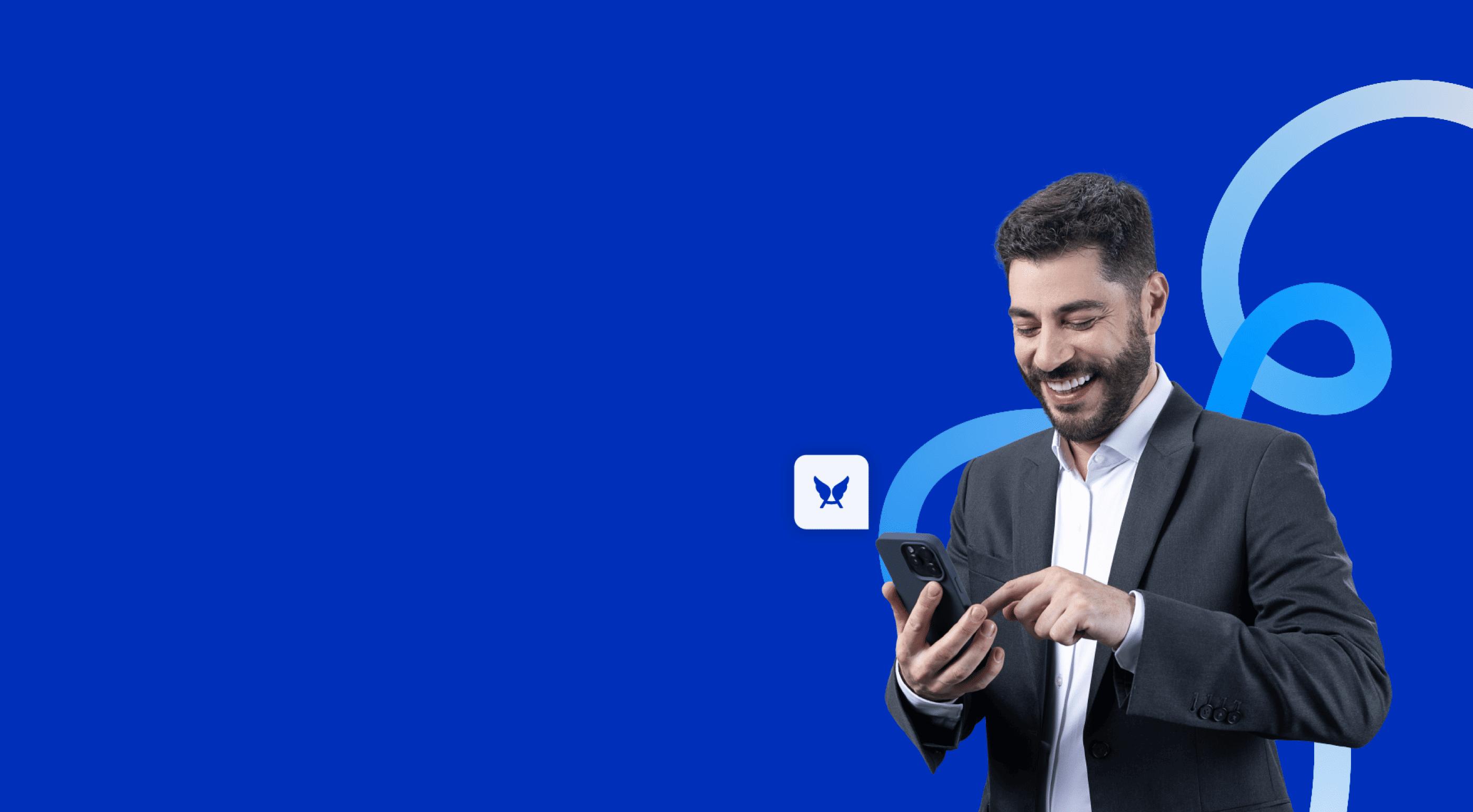 Evaristo Corta sorrindo e olhando para o celular em suas mãos. 