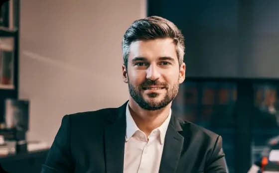 Empreendedor em um escritório olhando e sorrindo para a câmera.